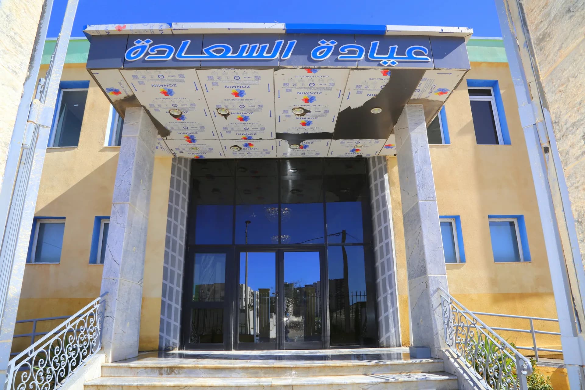 Entrée principale de la Clinique ESSAADA, auvent bleu avec inscription en arabe « عيادة السعادة »
