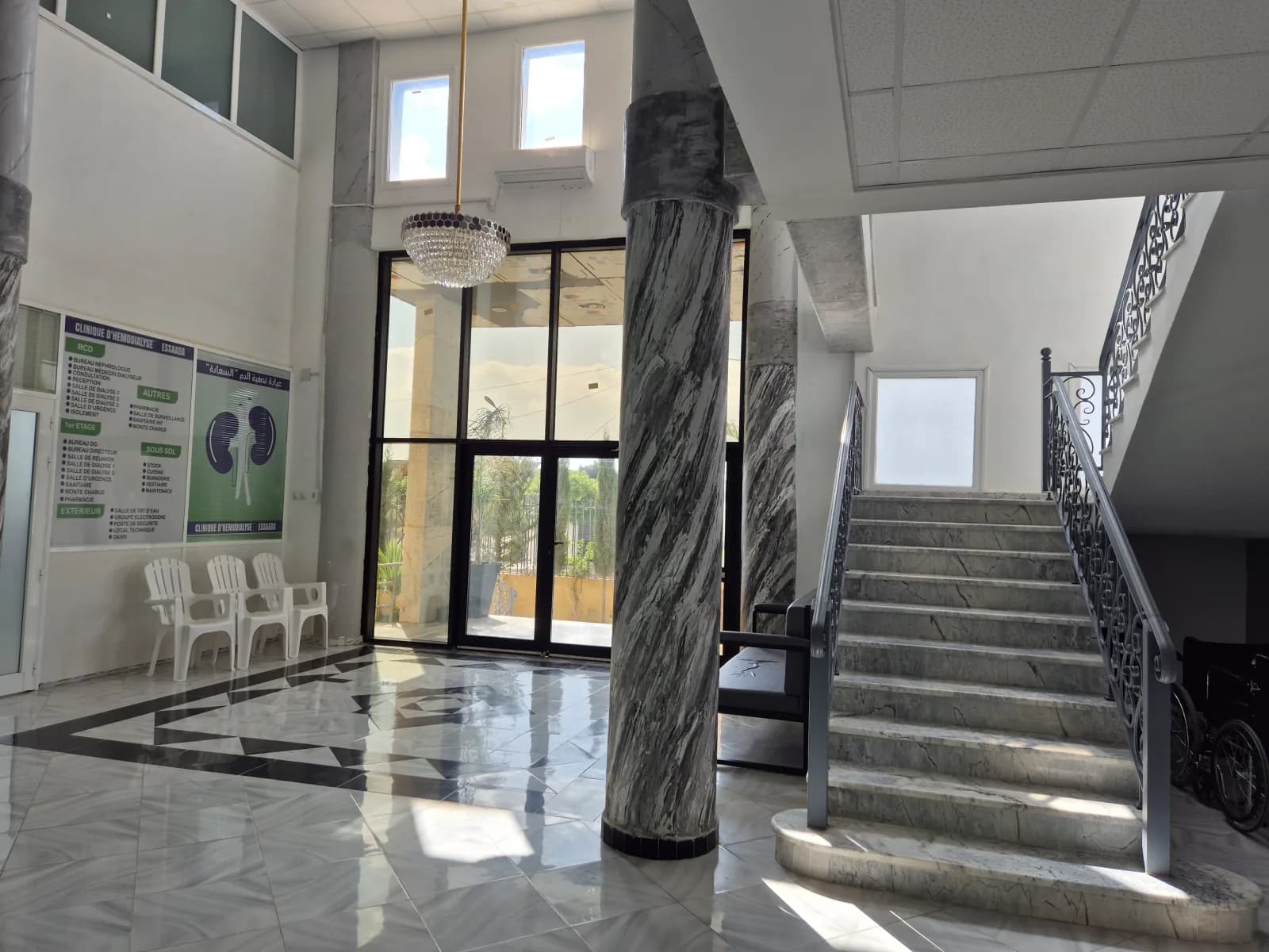 Hall principal de la Clinique d'Hémodialyse ESSAADA à Sidi Bel Abbès, escalier en marbre et panneau d'orientation des services
